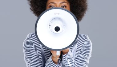 African,American,Woman,Speaking,Into,A,Megaphone,Making,A,Public